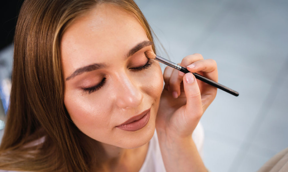 Mujer aplicando maquillaje en los párpados de una cliente