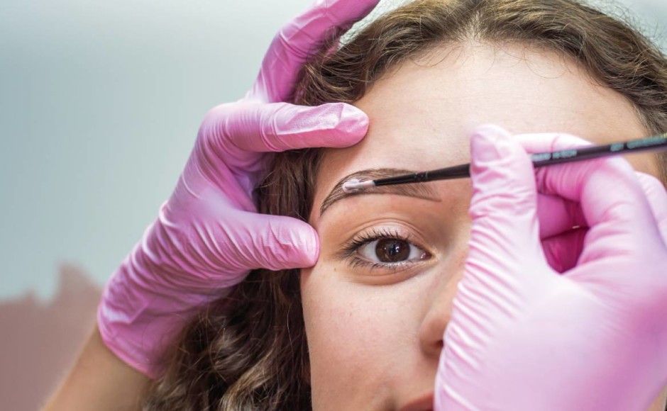 Mujer a la que se le está aplicando maquillaje en el contorno de las cejas