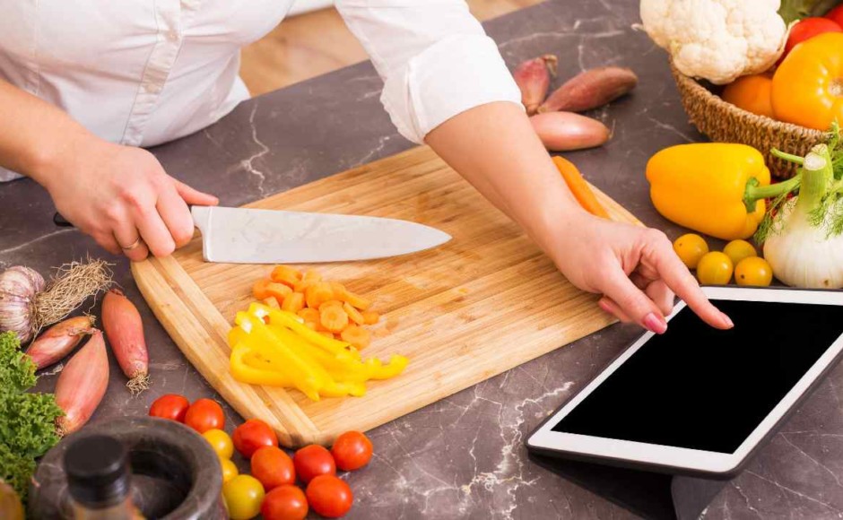 Manos de una persona aprendiendo a preparar una nueva receta en línea