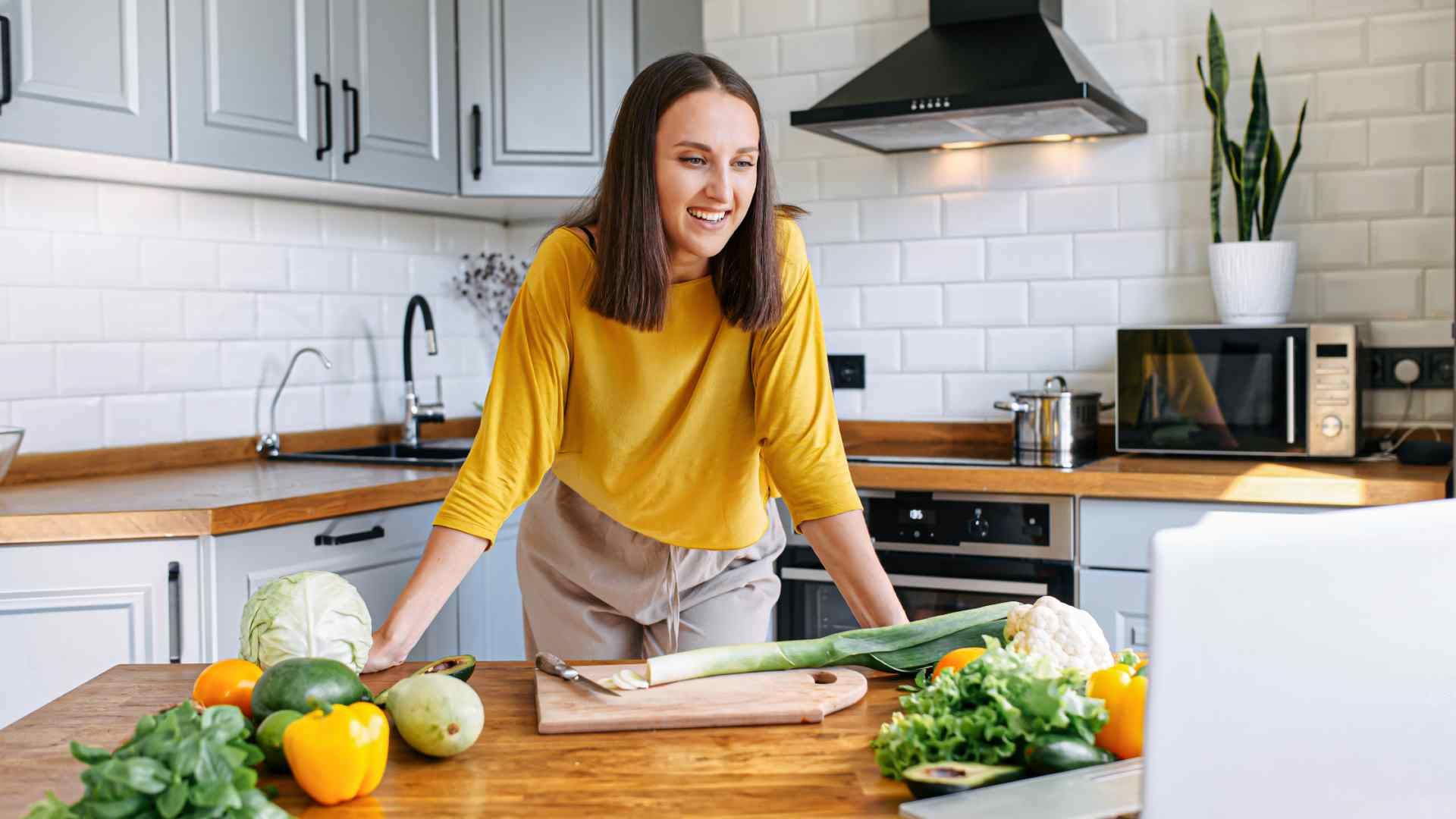 Mujer en su cocina frente a su computador portátil tomando un Diplomado de Cocina Internacional