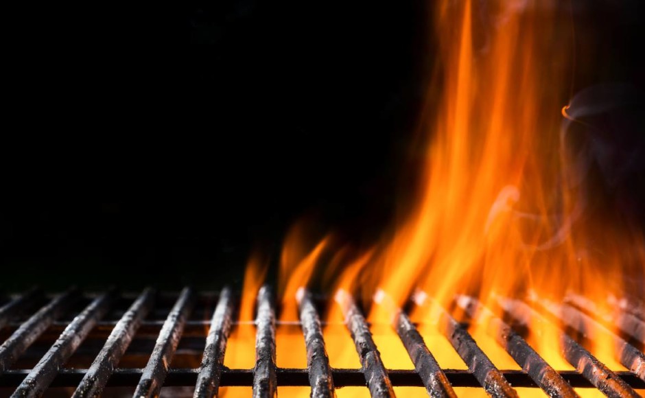 Llama de fuego saliendo de una parrilla para carne