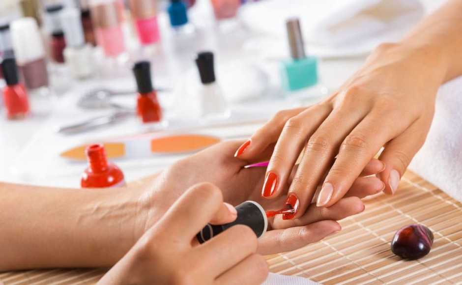 Manos de una mujer aplicando manicure a las manos de otra mujer