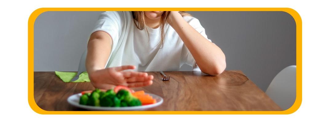 imagen de una mujer rechazando un plato con vegetales