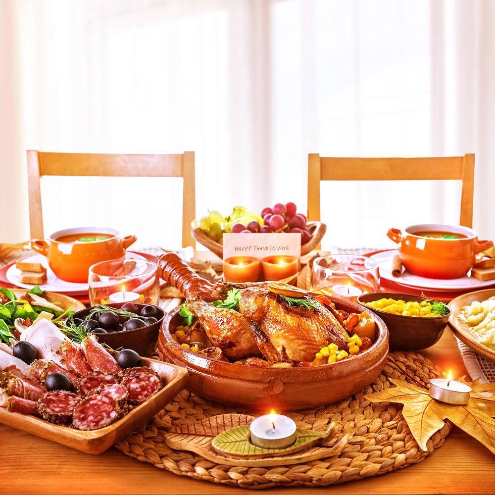 cena de thanksgiving con pavo y diferentes platos con una tarjeta de celebración