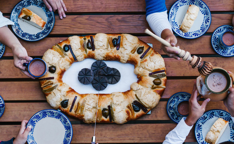 mesa con la tradicional rosca de reyes con una familia disfrutando el plato