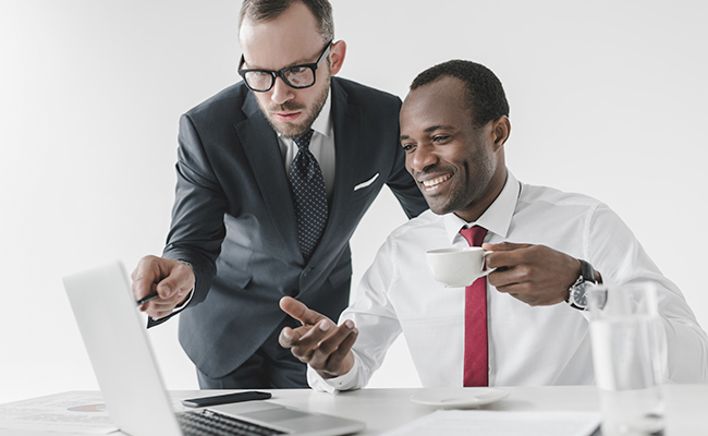 dos trabajadores conversando frente a un escritorio con computadora