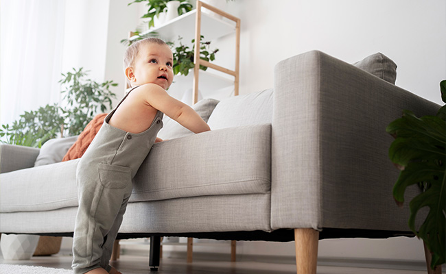 Bebé sosteniéndose con el sillon