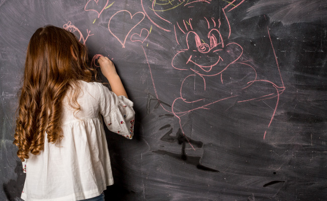 una niña haciendo alguna travesura, como rayando la pared