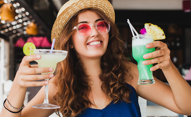 mujer disfrutando un cóctel en la playa