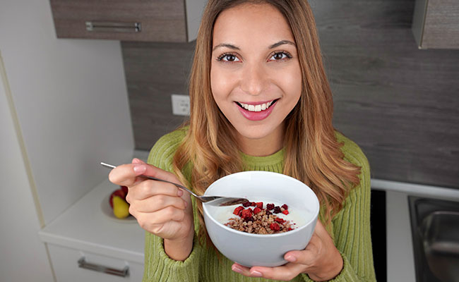 Una persona frente a la cámara con un plato de frutas y avena