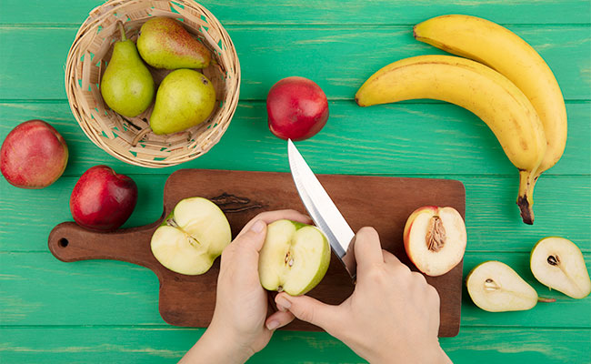 persona cortando manzana sobre una tabla