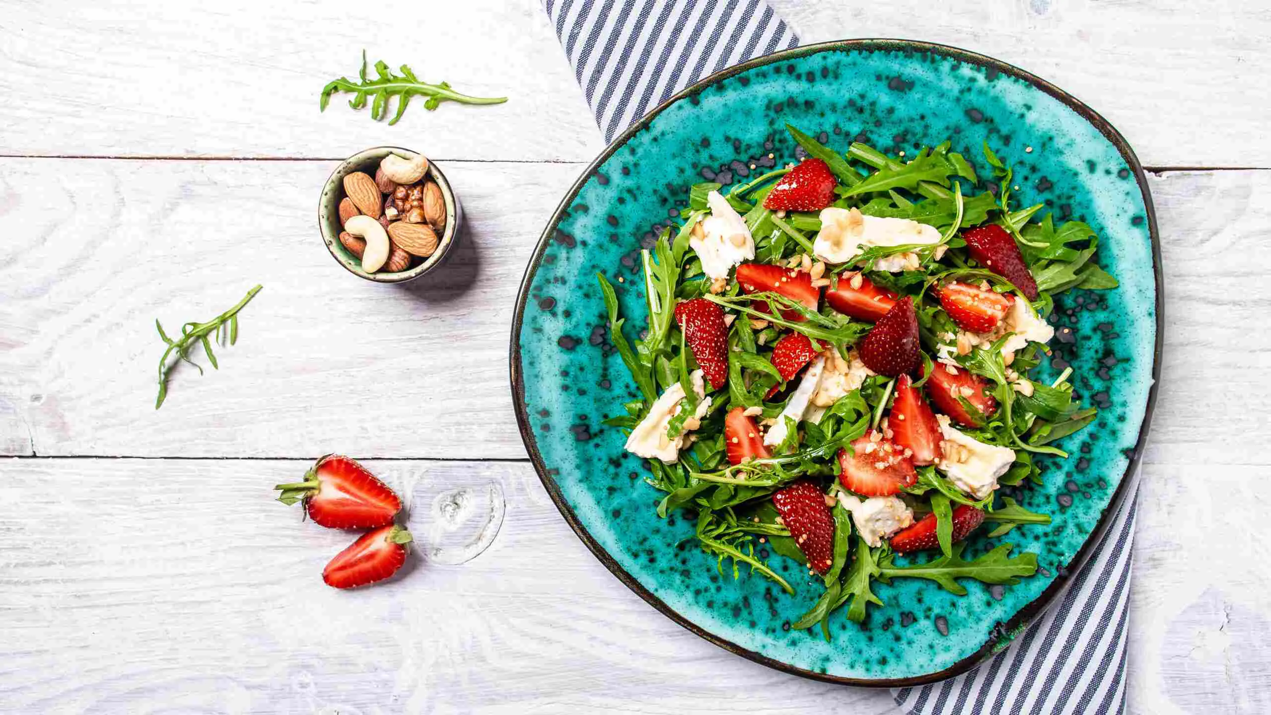 Ensalada en un bowl azulado con grandes trozos de queso y verdes