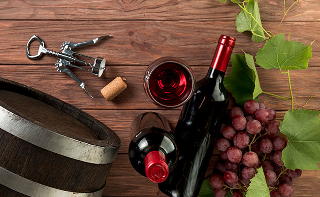 Una botella de vino sobre una mesa donde reposen a su lado un corcho y un sacacorcho