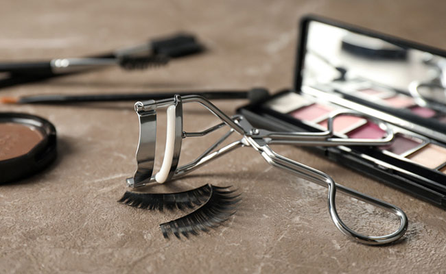 escritorio con espejo, pinzas, pegamento y pestañas postizas