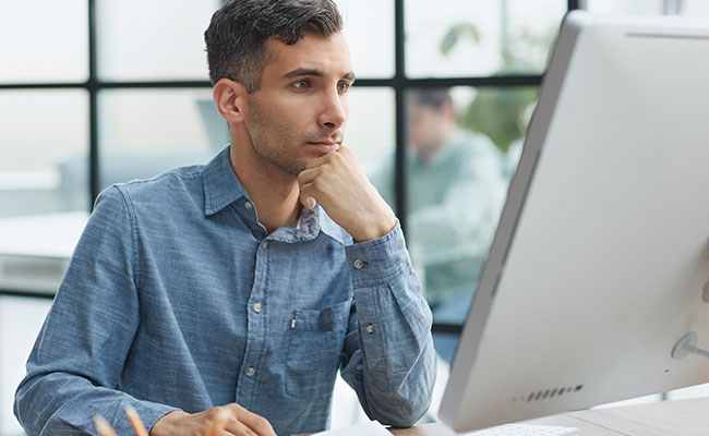 Hombre con camisa mirando el monitor de su computadora