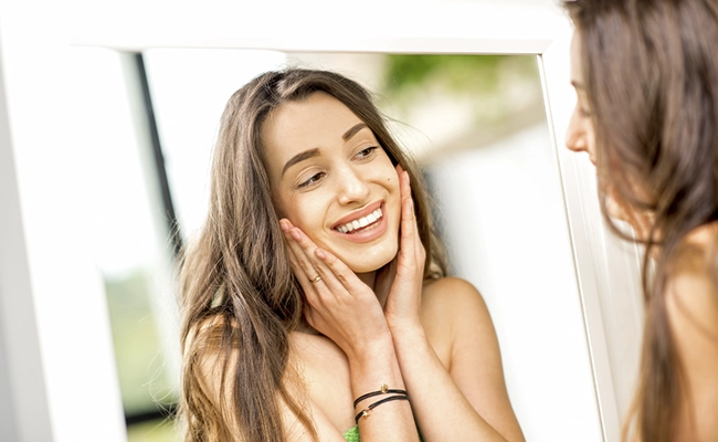 mujer mirándose al espejo y sonriendo