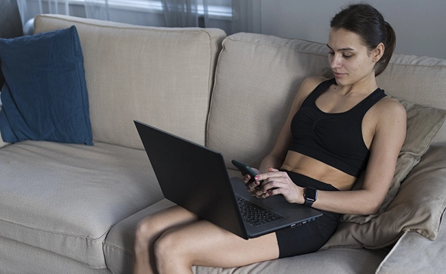 mujer vestida de deporte trabajando online en su computadora