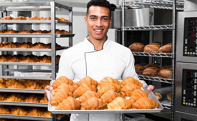 chef repostero con una bandeja de croissants